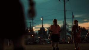 Youth soccer players on a field at dusk representing the participant injury risks covered by sport accident insurance.